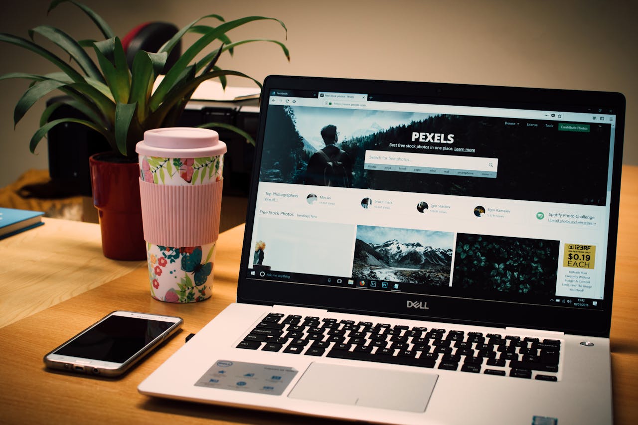 gallery-04 A tidy desk setting with a laptop showing a stock photo website and a smartphone.